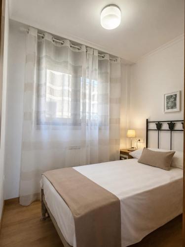 a bedroom with a large white bed and a window at Apartamento Alfa in Monforte de Lemos