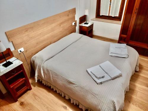 a bedroom with a white bed with a wooden headboard at Appartamento Sorapiss in Lorenzago