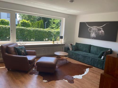 a living room with a green couch and a cow on the wall at Allgäu Bungalow GLOW in Isny im Allgäu