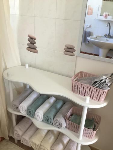 a bathroom with towels on a shelf and a sink at Marseillan in Marseillan