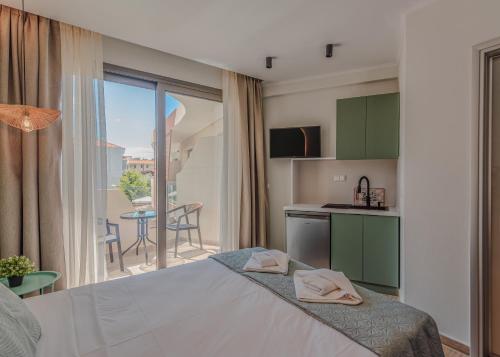 a bedroom with a bed and a kitchen with a balcony at The Wave in Limenaria