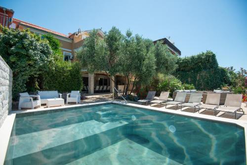 a swimming pool with chairs and a house at Vila Veslo in Begovići