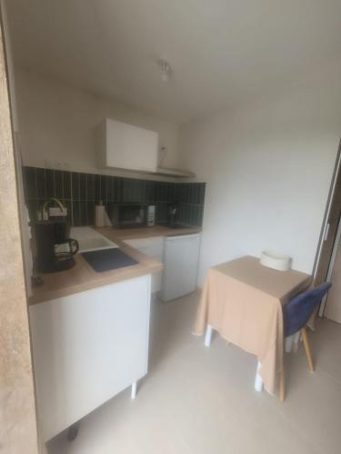 a small kitchen with a table and a chair at Maisonnette nature et sérénité in Évran