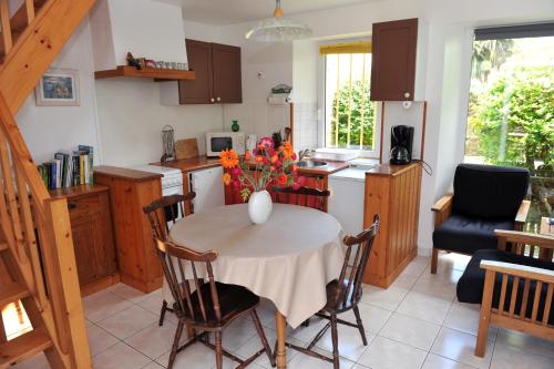 a kitchen with a table with a vase of flowers on it at Gite de Kergrist in Paimpol