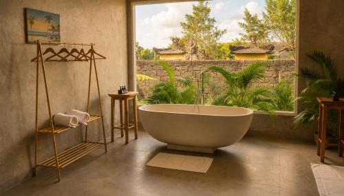 a bathroom with a large tub in front of a window at Bali Eco Retreat in Bangli