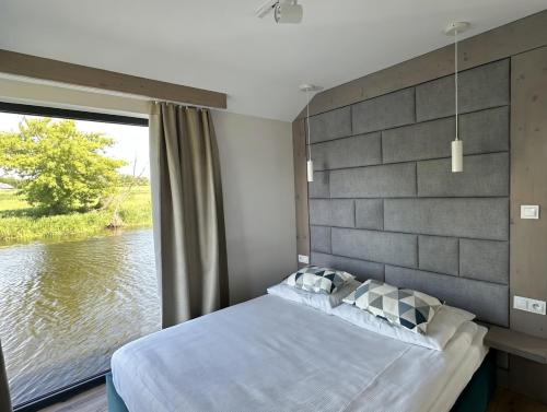 a bedroom with a large window overlooking a river at Pensjonat Bobrowy Dwór in Szelków Stary