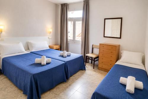 a bedroom with two beds and a chair and a window at L´Hostalet in Tossa de Mar