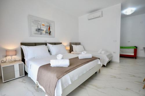 a white bedroom with two beds with towels on them at Villa Orkidea in Sarandë