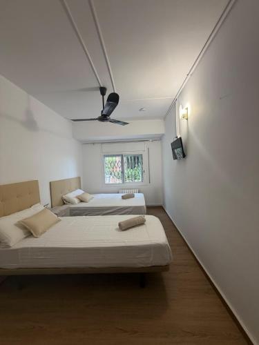 two beds in a room with white walls and a window at Miramar Viladecans in Viladecáns