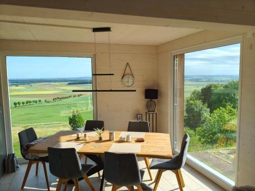 a dining room with a table and chairs and a large window at Morgenrot Panorama-Apartment 2 - Zwei Balkone in Gnotzheim