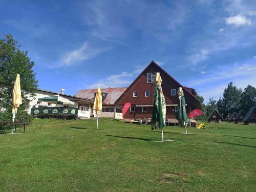a large building with closed umbrellas in the grass at Penzion Athena in Velenov