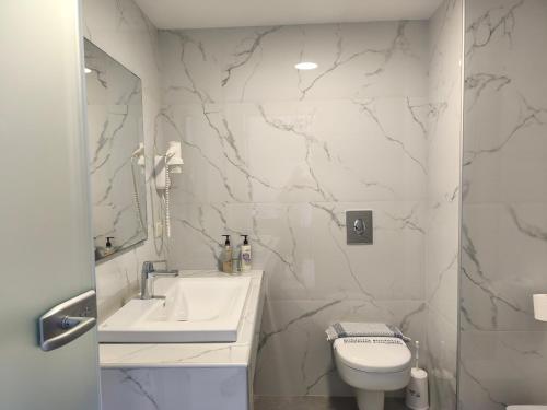 a white bathroom with a sink and a toilet at Aegean Blue Studios in Afitos