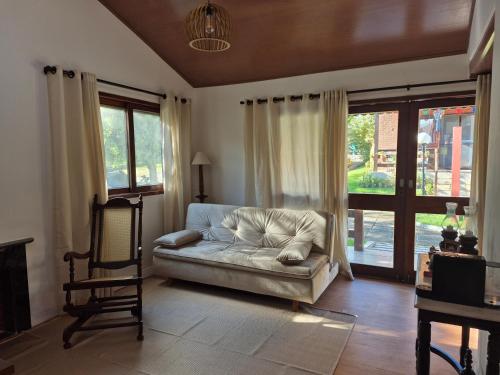 a couch sitting in a living room with windows at Privê Monte Serrat, Chalé 18 in Gravatá