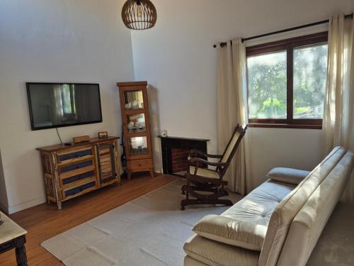 a living room with a couch and a tv and a chair at Privê Monte Serrat, Chalé 18 in Gravatá