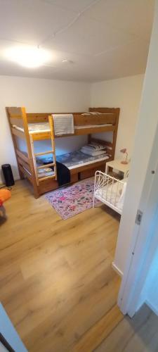 a room with two bunk beds and a wooden floor at Stuga PETEL in Färjestaden