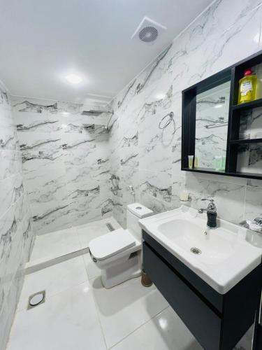 a white bathroom with a sink and a toilet at Tala Camp in Disah