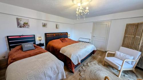 a bedroom with two beds and a chair and a chandelier at L'appart de saint léo in Saint-Léonard-de-Noblat