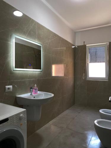 a bathroom with a sink and a washing machine at Mme apartment in Kamëz