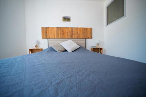 a large blue bed with two pillows on it at La Tomette - Gîte Eco Responsable - Le charme de l'authentique Climatisé in Maury