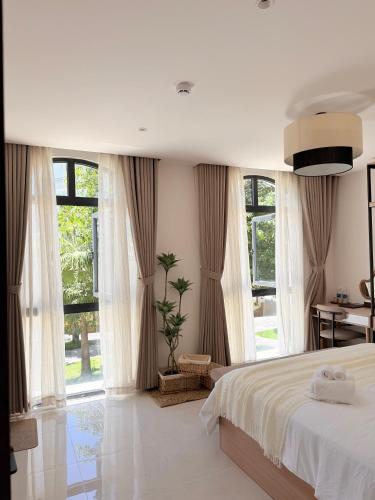 a bedroom with a bed and large windows at Olivea Boutique Hotel Phu Quoc in Phú Quốc