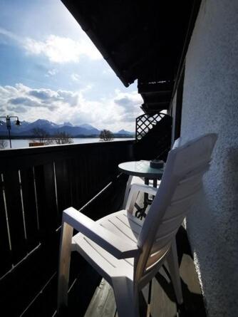 a balcony with a table and a white chair at Apartment mit Seeblick - Hopfen am See in Füssen