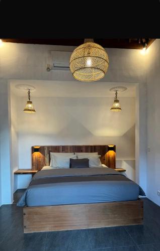 a bedroom with a large bed with two lights at SinCity Nature Private Pool Villa in Tanjung