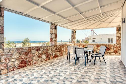a patio with a table and chairs and a stone wall at Floras House in Paradeísion