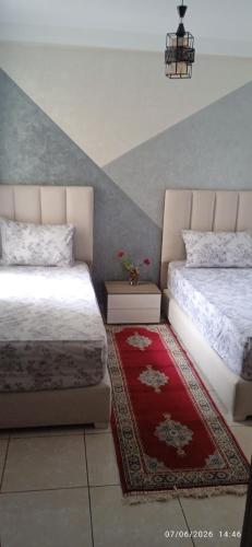 a bedroom with two beds and a red rug at Casa Farah Marjane in Tétouan