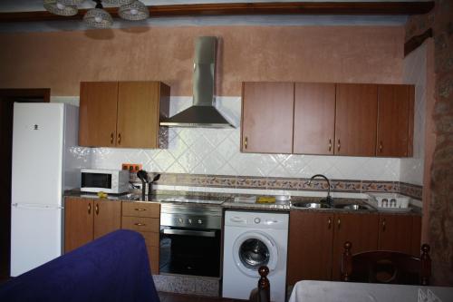 a kitchen with wooden cabinets and a washer and a dishwasher at Apartamentos Rio Mora in Mora de Rubielos