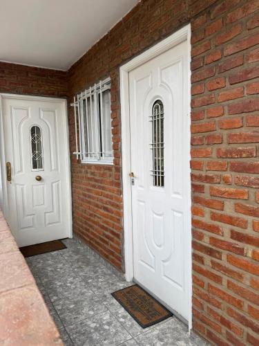 two white doors next to a brick wall at Departamento cercano al centro de Ezeiza in Ezeiza