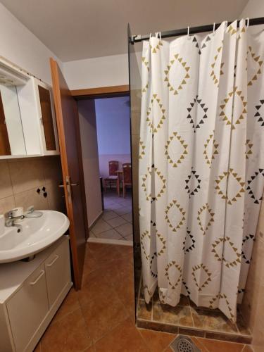 a bathroom with a shower curtain and a sink at Apartments Mali Raj in Vranjic