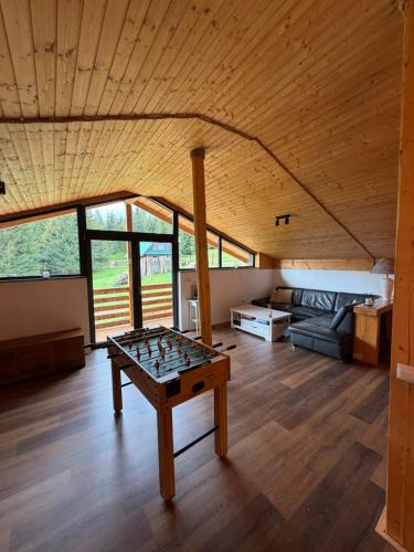 a living room with a foosball table in the middle at Greystone Cabin in Măguri-Răcătău