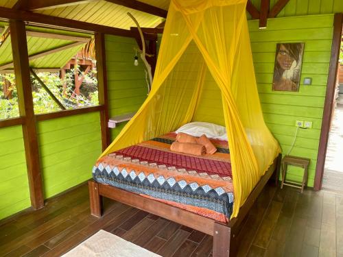 a bedroom with a bed in a green room at Kaz Robinson Cabane Perchee Vue Mer Vivez l aventure Robinson avec le confort d une vue imprenable sur les Caraibes in Terre-de-Bas