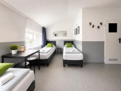 a room with two beds and a table in it at Grey Poznań Pokój z łazienką, Free Parking & Self Check-in in Poznań