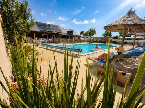a pool with two people sitting in chairs and an umbrella at Domaine MON CALME in Piriac-sur-Mer
