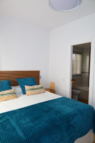a bedroom with a large bed with a blue blanket at Divi Apartments Costa Ballena in Costa Ballena