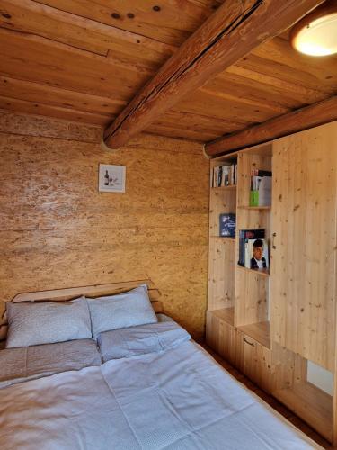 a bed in a room with a wooden wall at Guest house Oaze in Miglāni