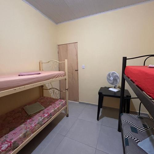 a room with two bunk beds and a table with a fan at Quarto bem próximo ao Pelourinho in Salvador