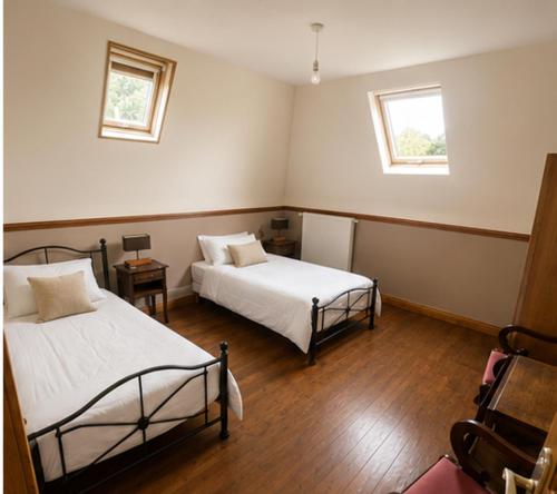 a bedroom with two beds and two windows at La Ferme des Coquelicots in Miraumont