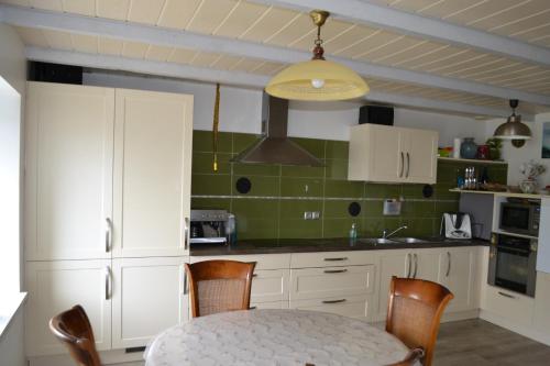 a kitchen with white cabinets and a table with chairs at maison pour vieilles charrues in Maël-Carhaix