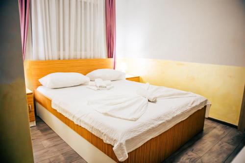 a bedroom with a bed with white sheets and a window at Hotel Nur in Mostar
