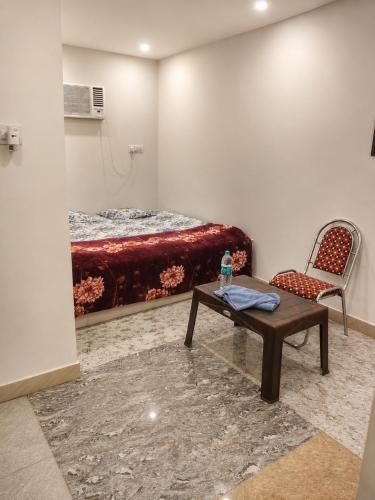 a room with a bed and a table and a chair at Hotel Janki Niwas - बाबा बैद्यनाथ मंदिर के निकट in Deoghar