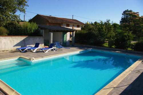 - une piscine avec 2 chaises longues et une maison dans l'établissement La Ferme de Menoun, à Thil
