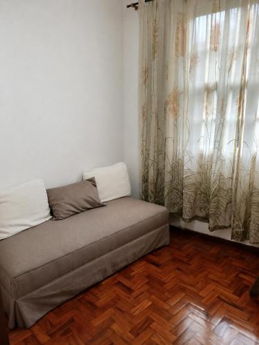 a couch sitting in a room with a window at Apt Petrópolis - Imperial in Petrópolis