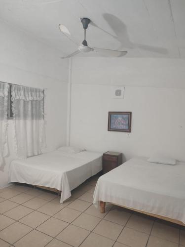 a bedroom with two beds and a ceiling fan at Hotel Caleta Bor Acapulco in Acapulco