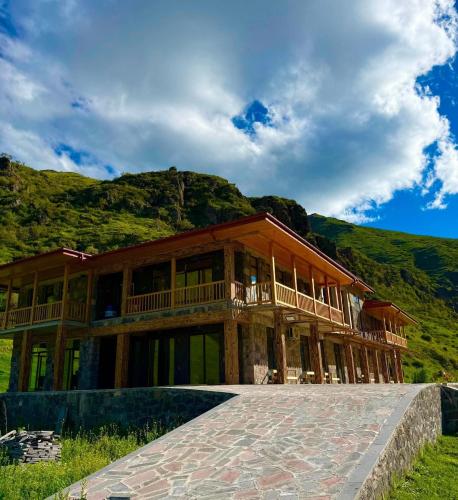 a large wooden house with mountains in the background at Vardzia Hills in Gogasheni