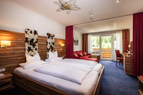 a hotel room with a large bed and a desk at Alm- & Wellnesshotel Alpenhof in Schönau am Königssee