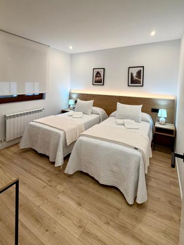 two beds sitting in a room with wooden floors at Laros Pios Alojamiento 4 in Villalba
