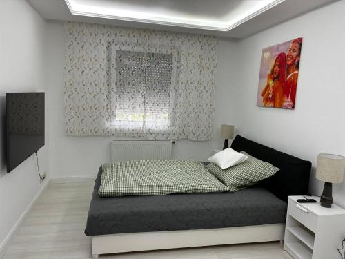 a small bedroom with a bed and a window at Bezsó apartman in Hajdúszoboszló
