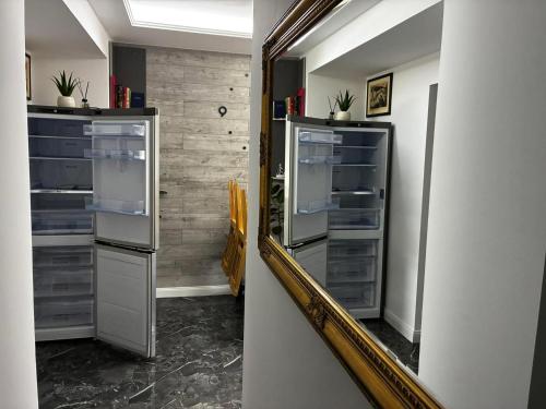 an empty refrigerator in a hallway with a mirror at Bezsó apartman in Hajdúszoboszló